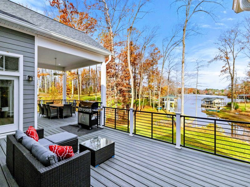 Elegant outdoor deck with a dining area, grill, cozy seating, and modern railings, perfect for entertaining or relaxing in style.