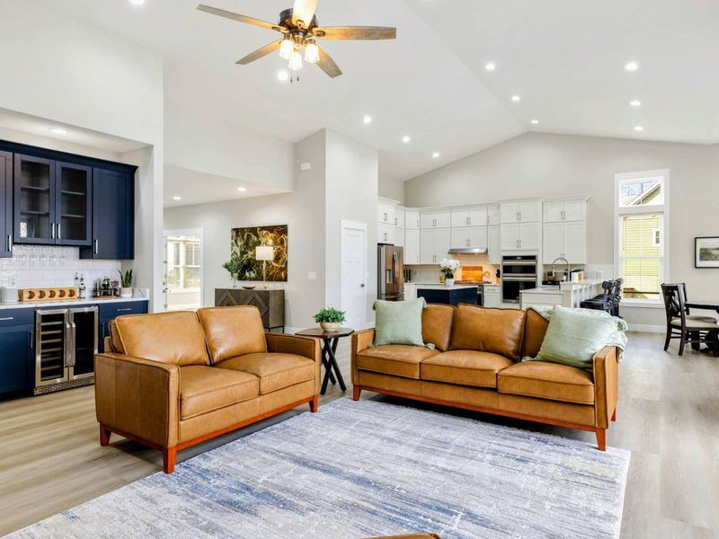 Open-concept living area featuring a cozy seating space, modern kitchen, and stylish wet bar, perfect for entertaining and relaxing.