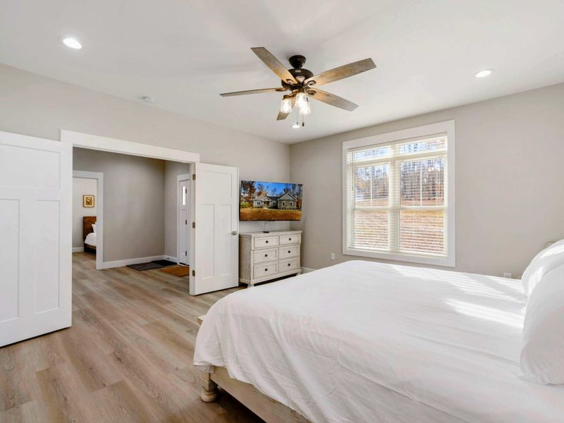 Bright and airy bedroom with a king-sized bed, elegant furnishings, large windows, and an en suite bathroom.