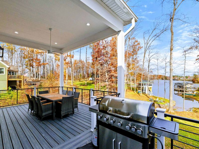 Elegant outdoor deck with a dining area, grill, cozy seating, and modern railings, perfect for entertaining or relaxing in style.