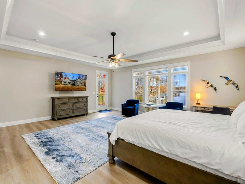 Elegant Primary Bedroom featuring a king-sized bed, stylish furnishings, a spacious layout, natural light from large windows, and an en suite bathroom for added convenience.