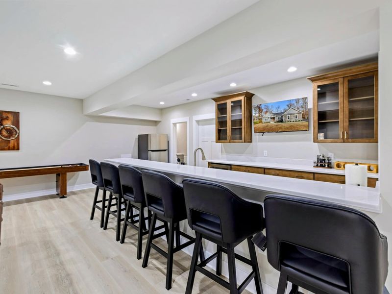 Spacious bar area with elegant wooden cabinetry, a sink, and plenty of counter space, seamlessly connected to the entertainment room.