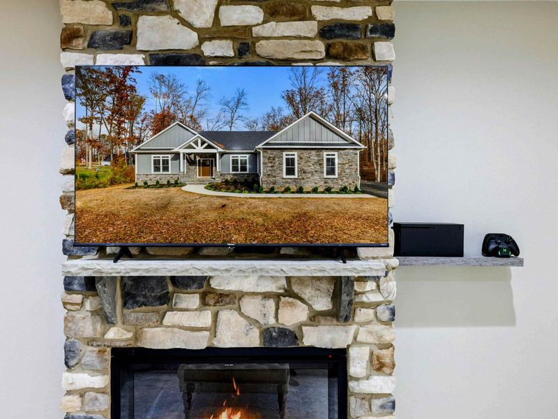 Stone fireplace with a mounted TV and a shelf for entertainment accessories, creating a warm and functional focal point in the living area.