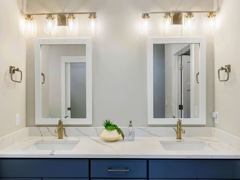 Luxurious en suite bathroom with a freestanding soaking tub, double vanity with navy cabinets, a walk-in shower, and elegant finishes.
