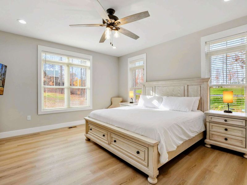 Bright and airy bedroom with a king-sized bed, elegant furnishings, large windows, and an en suite bathroom.
