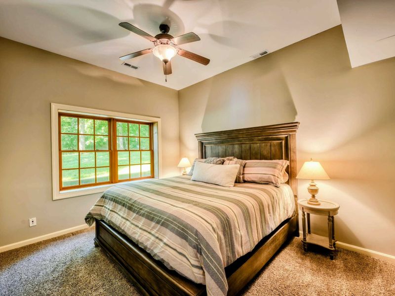 A tranquil bedroom features a plush king bed, elegant wooden furniture, and soft lighting, creating a cozy and inviting atmosphere.
