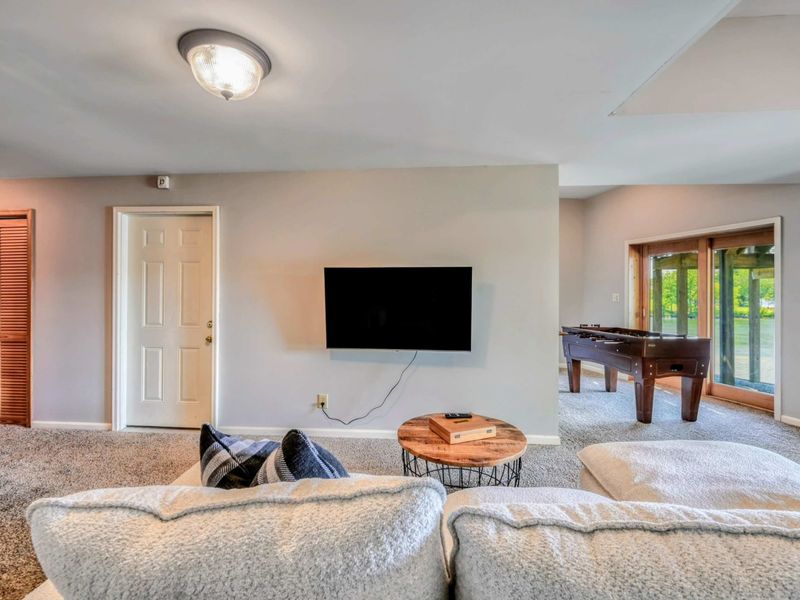 The airy space blends a cozy seating area, a foosball table, and serene lake views for the ultimate getaway.