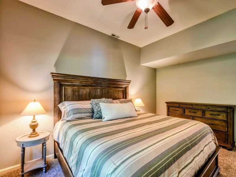 A tranquil bedroom features a plush king bed, elegant wooden furniture, and soft lighting, creating a cozy and inviting atmosphere.