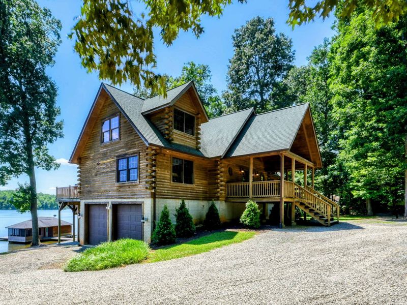 Charming waterfront home with a picturesque front porch surrounded by lush greenery and stunning lake views.