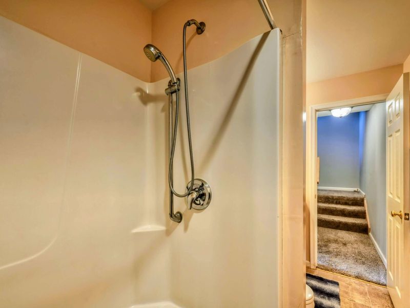 A clean and functional bathroom features a walk-in shower, a single vanity with ample counter space, and soft lighting for a comfortable experience.