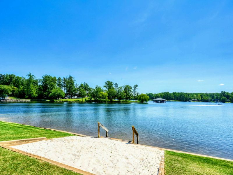 Private sandy beach area with steps leading into the clear, tranquil lake waters.