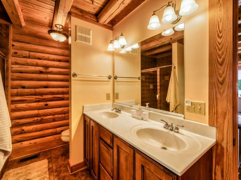A luxurious en suite bathroom features a jetted soaking tub, a spacious walk-in shower, double sinks with a large vanity, and warm wood accents for a cozy yet elegant retreat.