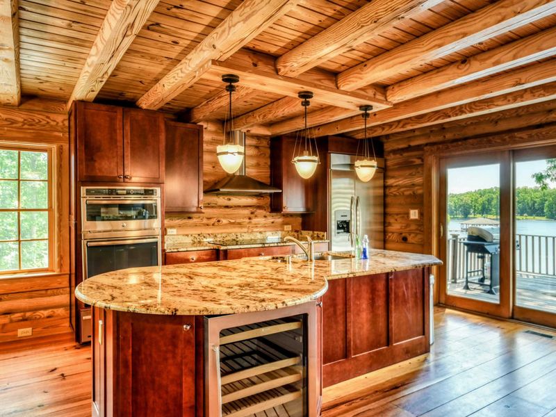 A spacious kitchen with granite countertops and wood cabinetry opens to a deck with stunning lake views.