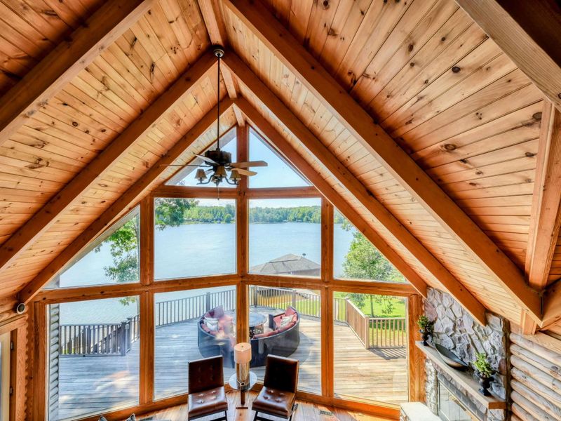 A breathtaking loft view showcases vaulted wooden ceilings, expansive windows, and stunning lake scenery below.