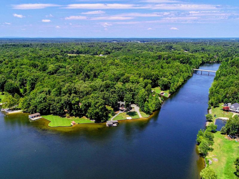 Expansive aerial view of a tranquil lake surrounded by lush forests and a private waterfront property.