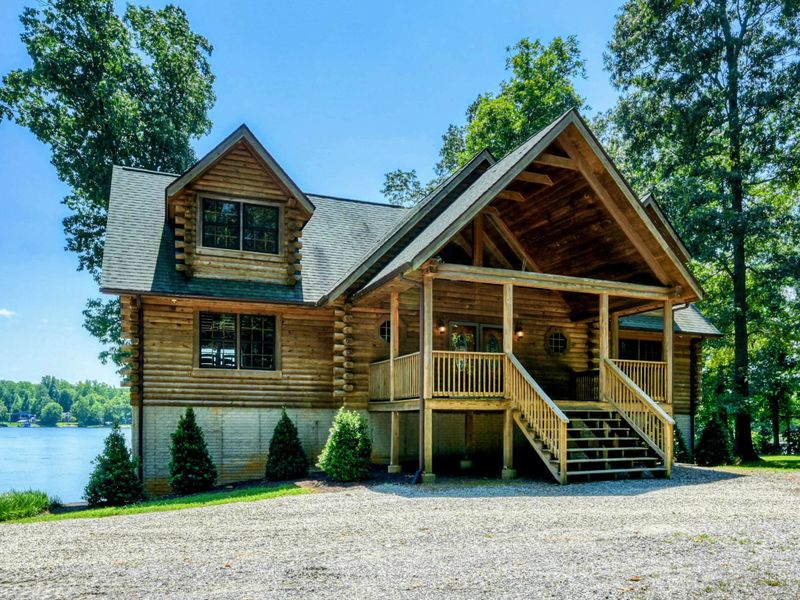 Charming waterfront home with a picturesque front porch surrounded by lush greenery and stunning lake views.