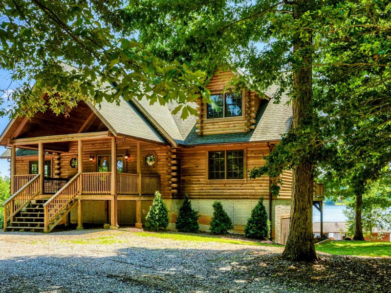 Charming waterfront home with a picturesque front porch surrounded by lush greenery and stunning lake views.