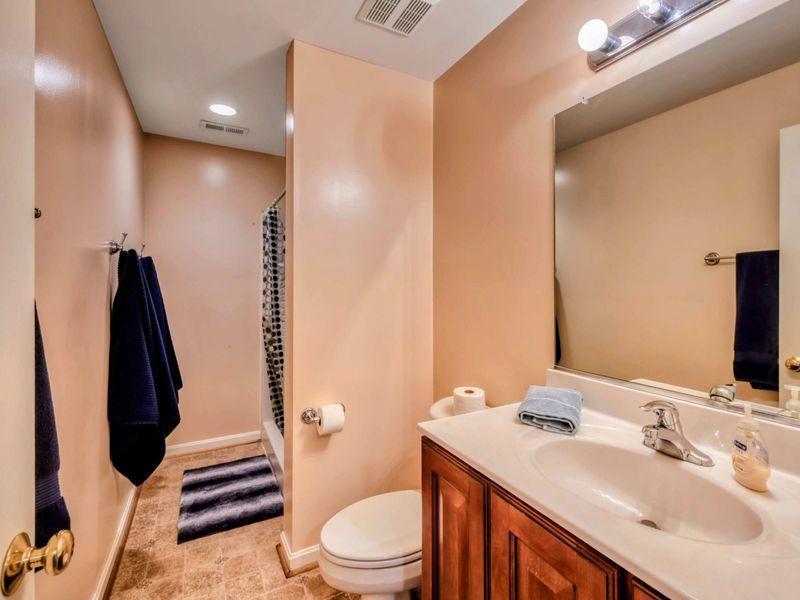 A clean and functional bathroom features a walk-in shower, a single vanity with ample counter space, and soft lighting for a comfortable experience.