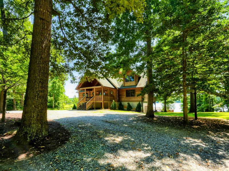 Charming waterfront home with a picturesque front porch surrounded by lush greenery and stunning lake views.