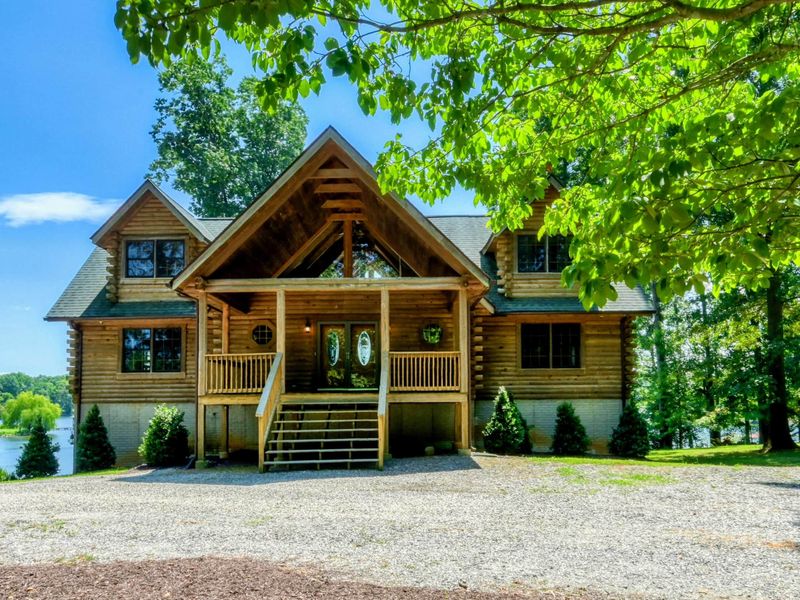 Charming waterfront home with a picturesque front porch surrounded by lush greenery and stunning lake views.