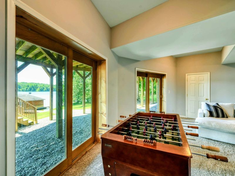 A bright and inviting game room features a foosball table and large glass doors with lake views.
