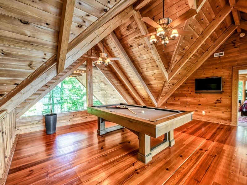 A stylish and airy loft combines modern amenities like a TV with the rustic charm of natural wood and a pool table.