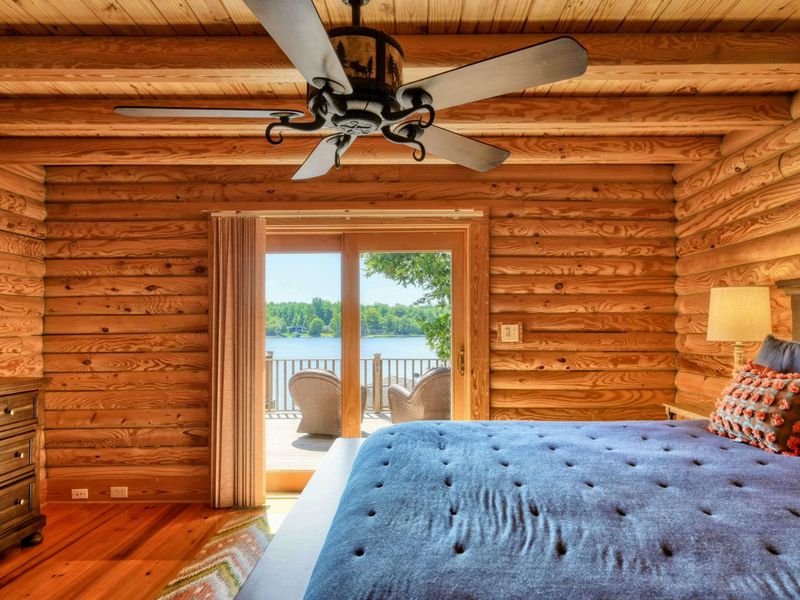 A cozy bedroom with a king-size bed opens to a private deck offering stunning lake views and includes an en suite bathroom.
