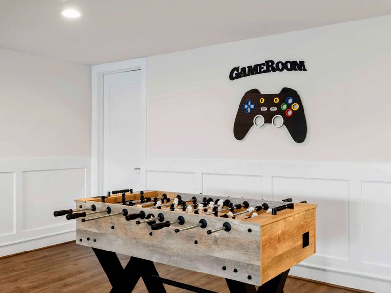 This spacious game room features a comfortable seating area with a modern fireplace, a pool table, ping-pong table, foosball table, shuffleboard, and a well-equipped kitchenette, all with stunning lake views.