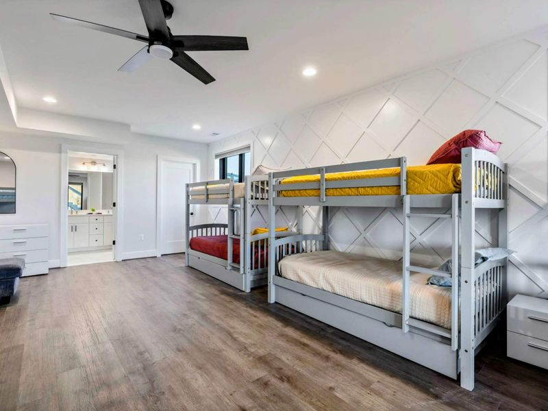 A spacious bunk room featuring 12 twin beds, modern decor, large windows with lake views, and an ensuite bathroom for group convenience.