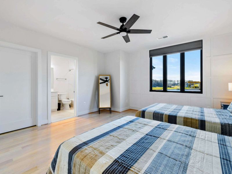 A cozy bedroom featuring two double beds, stylish decor, large windows with serene views, and an ensuite bathroom for added convenience.