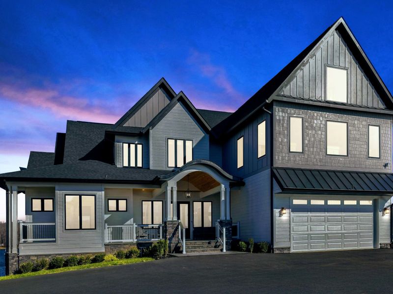 Exterior - The home at twilight with garage doors lit and the lake just out of frame to the right.