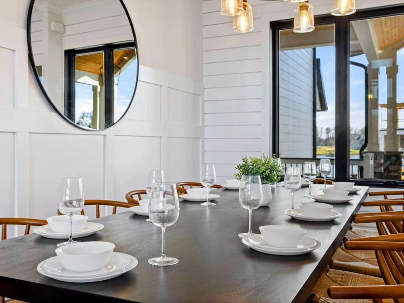 This dining area features a spacious table that seats eight, accented by modern lighting, large windows with lake views, and seamless integration into the open concept living space.