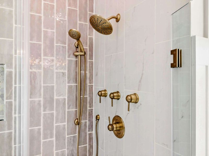 A luxurious en suite bathroom featuring dual vanities, a freestanding soaking tub with scenic views, and a spacious glass-enclosed shower with elegant tile and gold fixtures.