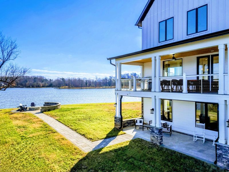 Exterior - The back of the home from the lawn: two-story porch, full lake-side glass, the deck and patio that catch the afternoon sun.