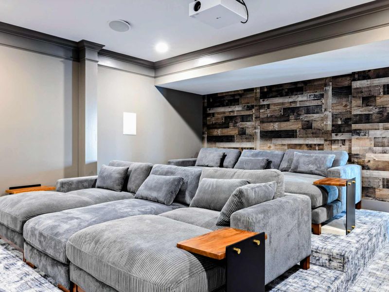 A dedicated home theater with tiered seating, plush couches, a large projector screen, and cozy cinema-themed decor for an immersive movie experience.