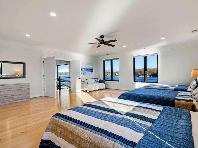A spacious bedroom with three beds, stunning lake views from every window, a cozy seating area, and a private en suite bathroom for added convenience.