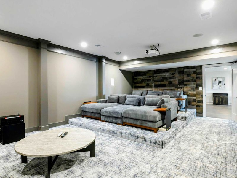A dedicated home theater with tiered seating, plush couches, a large projector screen, and cozy cinema-themed decor for an immersive movie experience.