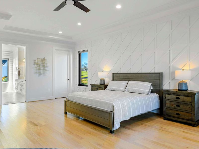 This spacious primary bedroom features a comfortable bed, a private seating area, access to a balcony with stunning lake views, and an en suite bathroom for added convenience.
