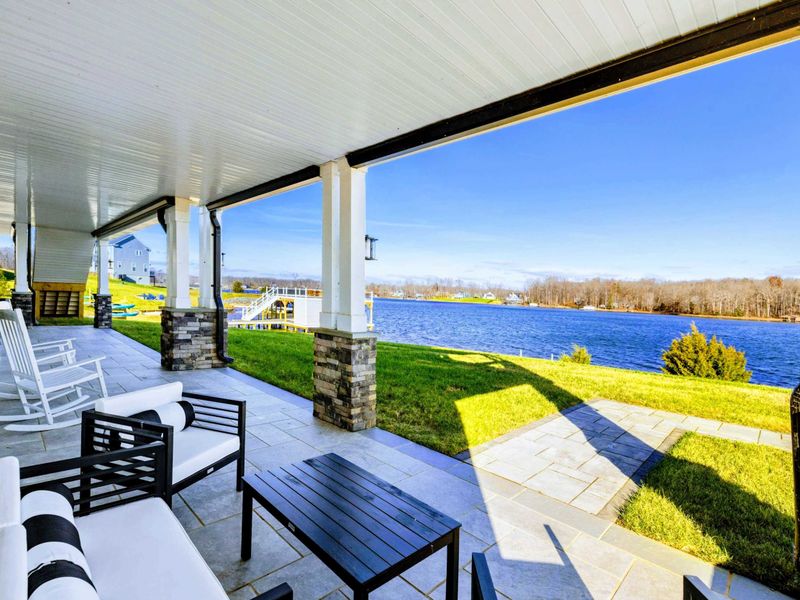 A covered patio with comfortable seating overlooking the lake, ideal for enjoying peaceful waterfront views.