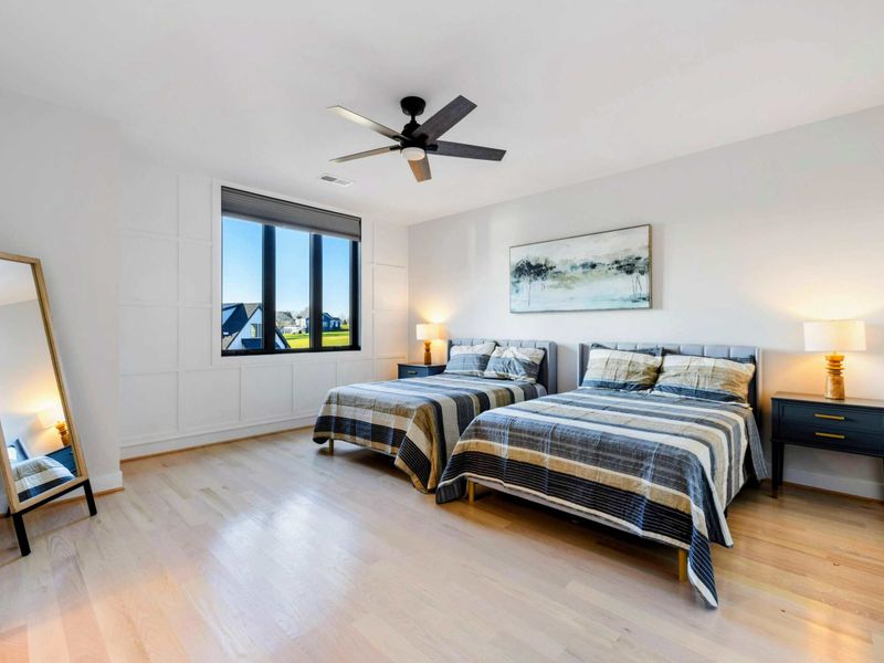 A cozy bedroom featuring two double beds, stylish decor, large windows with serene views, and an ensuite bathroom for added convenience.