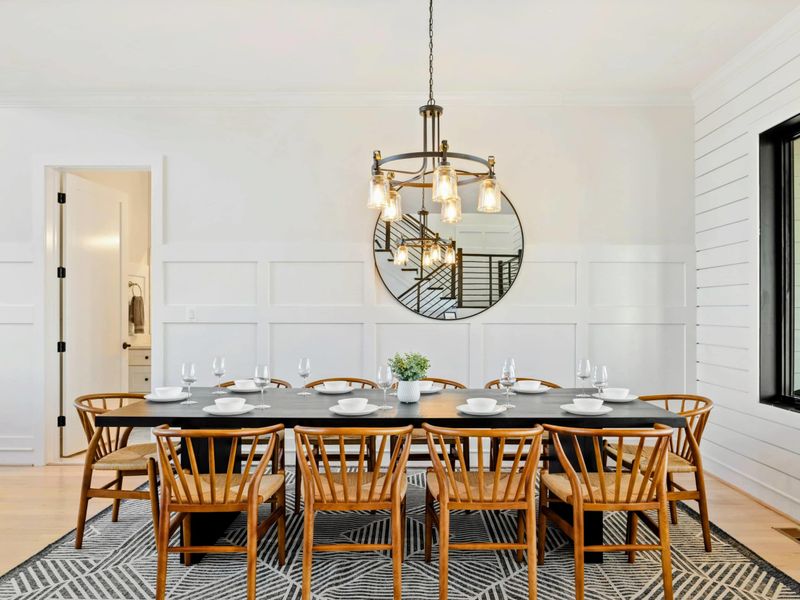 This dining area features a spacious table that seats eight, accented by modern lighting, large windows with lake views, and seamless integration into the open concept living space.