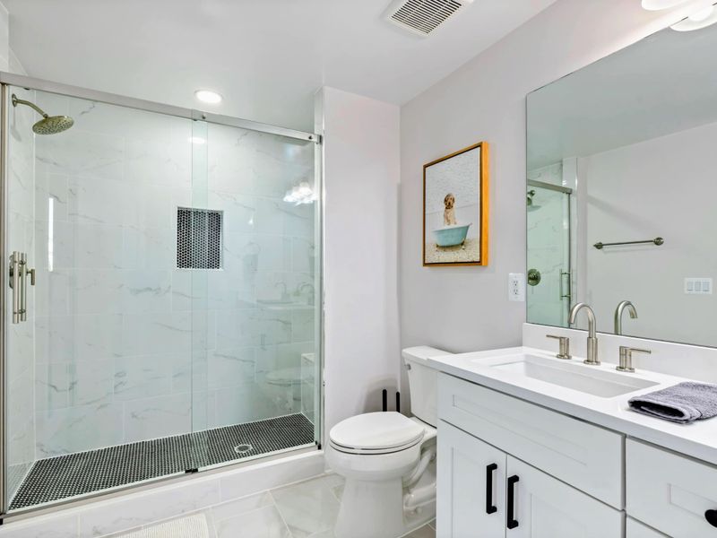 A modern ensuite bathroom featuring a spacious glass-enclosed shower, a double vanity with sleek fixtures, and elegant tile finishes for a luxurious touch.