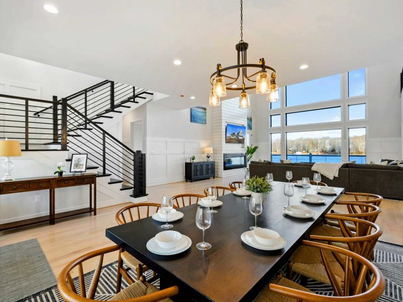 Dining Room - A long table that seats ten under a wrought-iron chandelier, with floor-to-ceiling windows pulling the lake right into dinner.