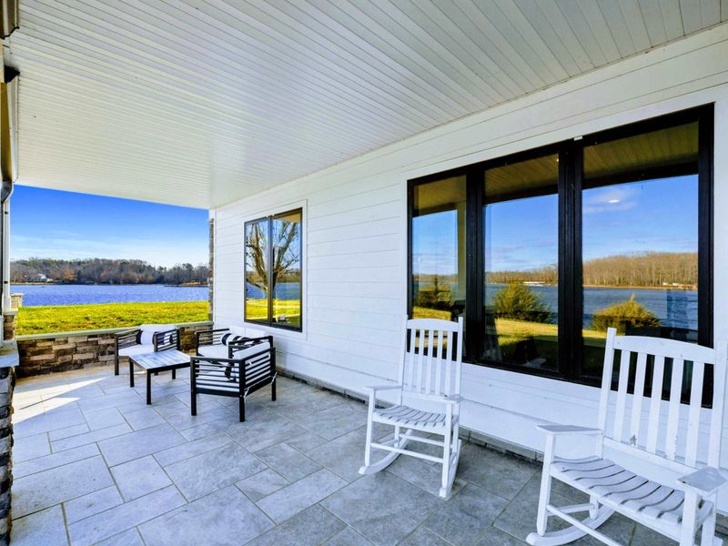 A covered patio with comfortable seating overlooking the lake, ideal for enjoying peaceful waterfront views.