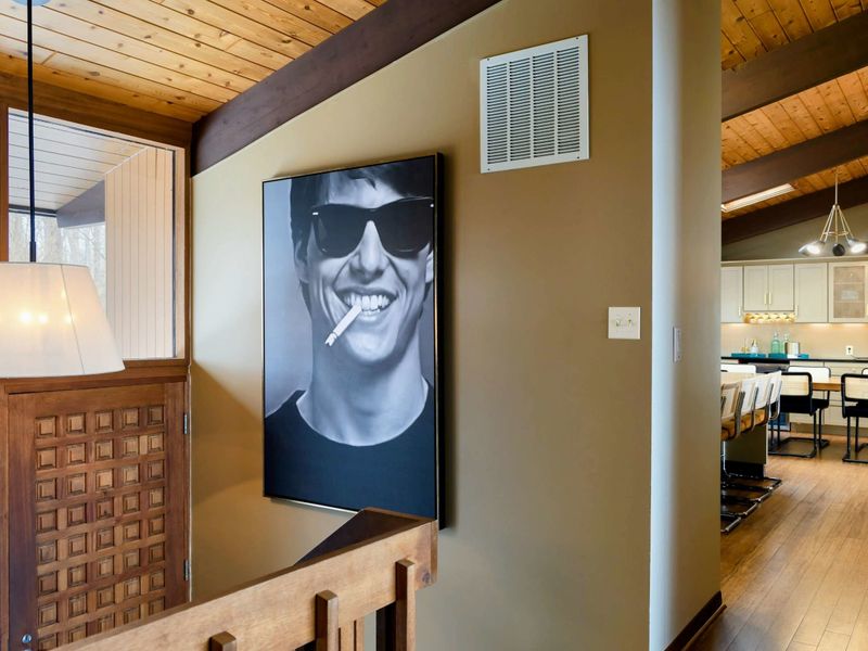 The stylish entryway exudes character with its bold art and warm wood tones, seamlessly connecting to the home for a welcoming and vibrant atmosphere.