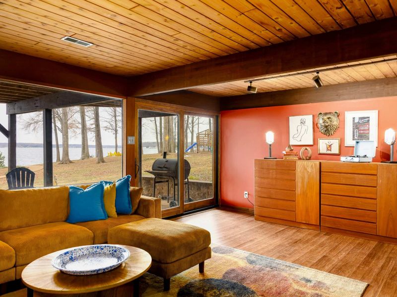 This inviting space offers expansive views of the outdoors through large glass doors, providing natural light and easy access to the yard. A stylish dresser and curated artwork add charm and functionality.
