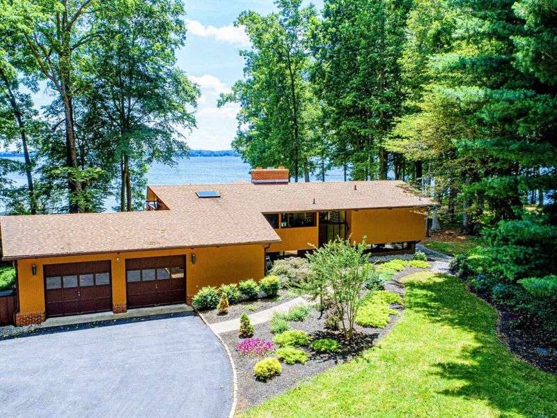 A stunning lakefront property surrounded by lush greenery, offering picturesque views and a serene retreat.