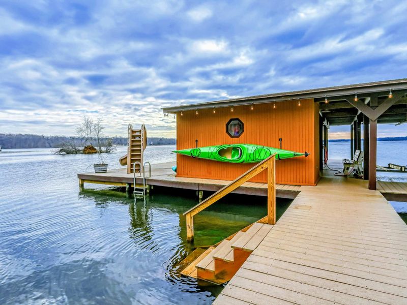 Lakefront boathouse with a water slide, kayak, and easy access to fun activities on the water.