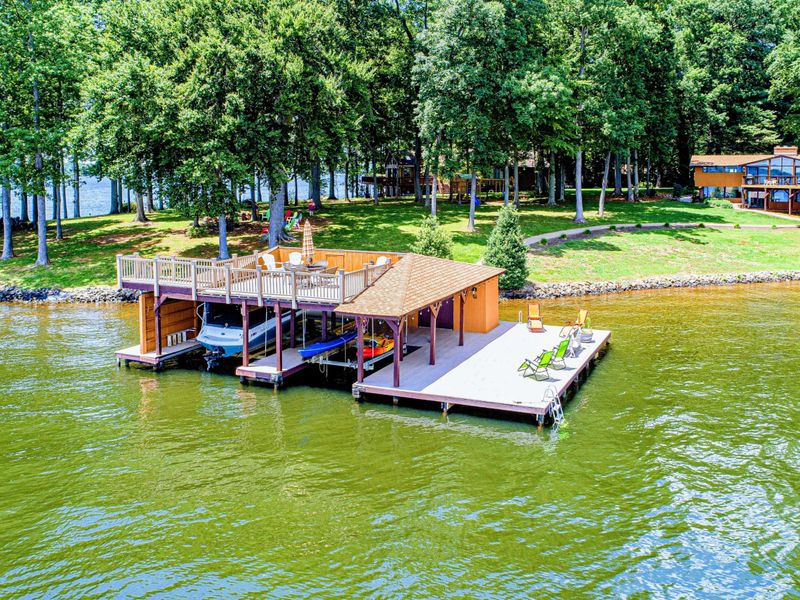 Private waterfront boathouse with an upper-level deck, boat slips, and a spacious sunbathing area overlooking the lake.