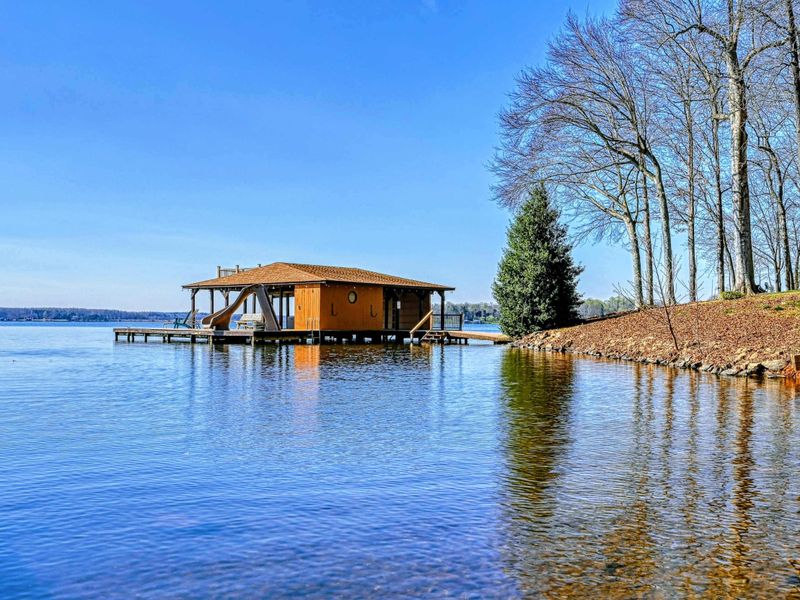 Lakefront boathouse with a water slide, kayak, and easy access to fun activities on the water.